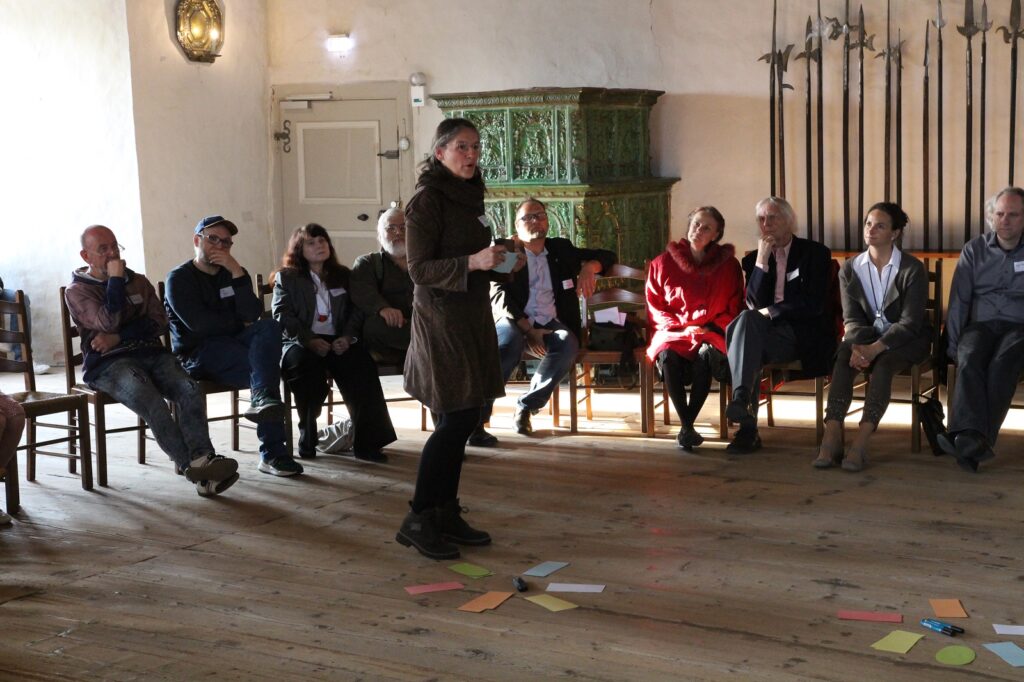 Eine Kulturakteurin steht in der Mitte des Sitzkreises und spricht.