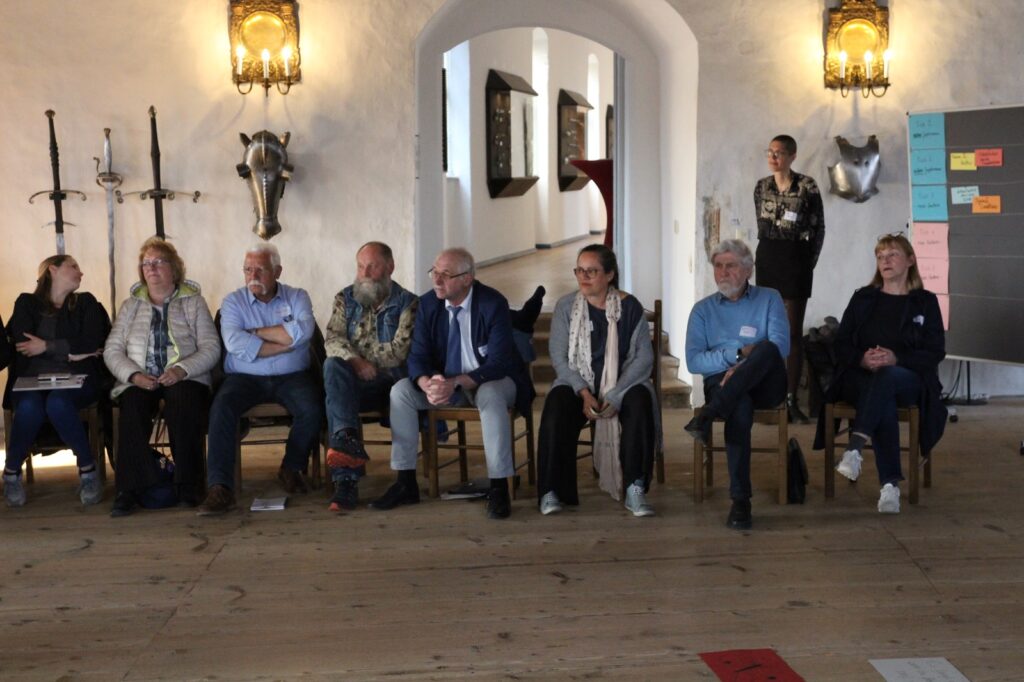 Kulturakteure im Sitzkreis hören jemandem zu.